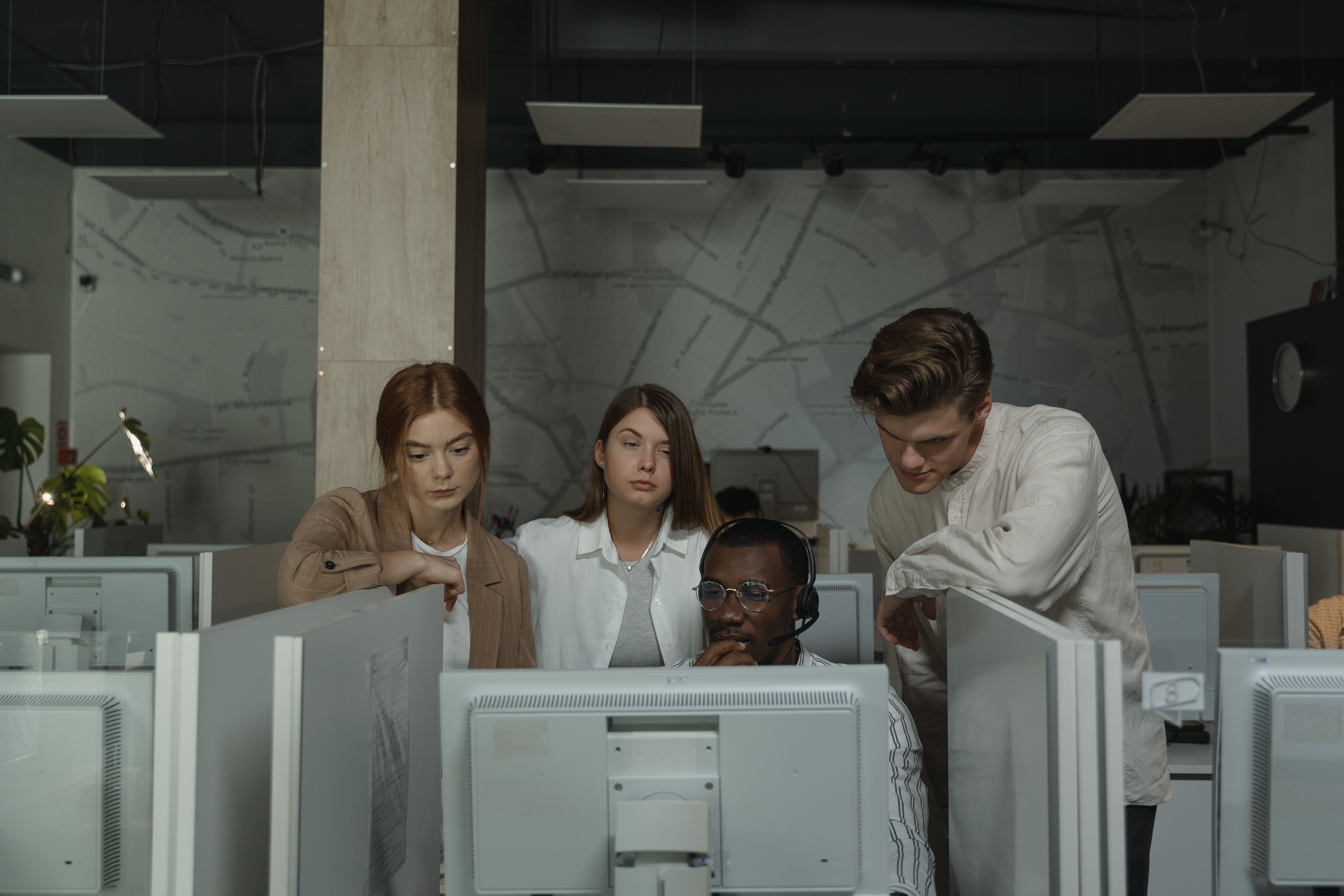 A team gathered around a colleague's screen in an open office